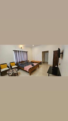 a living room with a bed and a flat screen tv at Fourseason frankcottage in Chikmagalūr