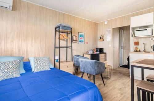 a bedroom with a blue bed and a kitchen at La chambre des oliviers in Aubais