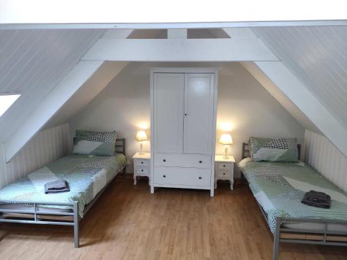 a attic room with two beds and a cabinet at Gîte à la Ville in Rostrenen