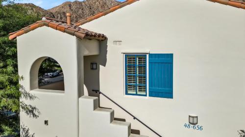 a white house with a blue window and stairs at LV250 Upstairs 2 BDR Condo with Private Balcony in La Quinta