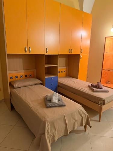 zwei Betten in einem Zimmer mit orangefarbenen Schränken in der Unterkunft frizzi house in Parabita