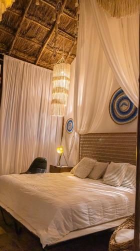 a bedroom with a white bed with curtains at Aldea Boutique Ommi in Progreso