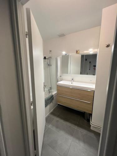 une salle de bain avec un lavabo, une baignoire et un miroir dans l'établissement Appartement 40 m2 avec parking gratuit, à Nanterre