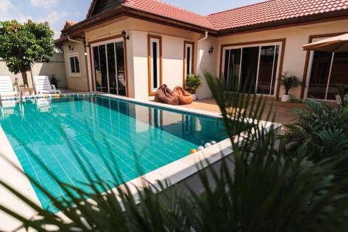 a swimming pool in front of a house at Queen Massarossa Pool Villa Pattaya-25 in Pattaya