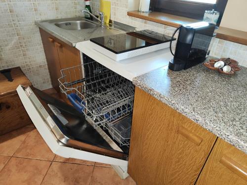 an open dishwasher in a kitchen next to a sink at Holiday house Panorama in Ozalj