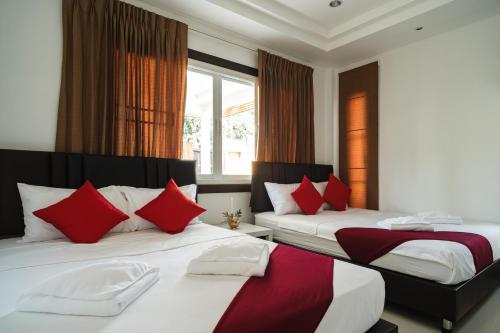 a bedroom with two beds with red and white pillows at Queen Massarossa Pool Villa Pattaya-25 in Pattaya Central