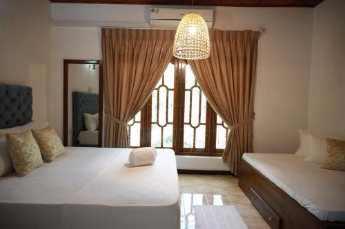 a bedroom with two beds and a large window at ALTURA Kandy By Ceylon Vistas in Kandy