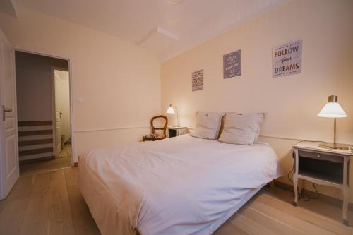 a bedroom with a large white bed and a night stand at Gîtes Fixey 1 et 2 in Fixin