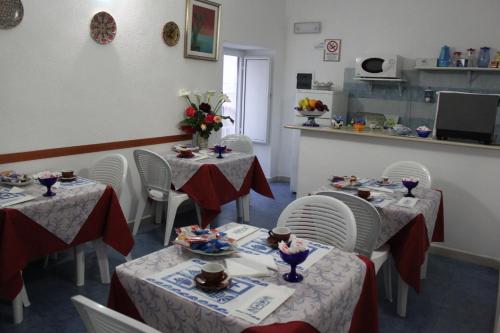 a dining room with two tables and white chairs at Albergo Locanda Sul Mare in Ischia