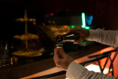 a person pouring a bottle of wine into a glass at Casa Suzanna Hotel Tel-Aviv קאסה סוזנה נחלת בנימין in Tel Aviv