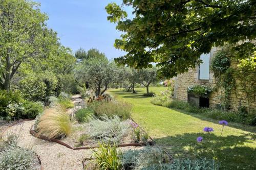 un jardin avec des plantes et des arbres et un bâtiment dans l'établissement Mas des Papillons Gordes, à Gordes