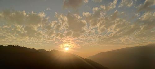 a sunset over a mountain with the sun in the sky at Subba Homestay Sukhia Pokhari Ramjee Road in Sukhia Pokhari