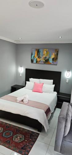 a bedroom with a large bed with two pink pillows at Grand Diamond Lodge in Roodepoort
