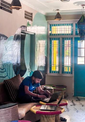 a man sitting on a couch using a laptop at Jungle by sturmfrei Jaipur in Jaipur
