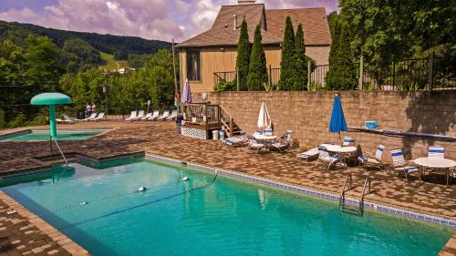 a swimming pool with chairs and umbrellas and a house at Big Bear Bend Gatlinburg Chalet Village in Gatlinburg
