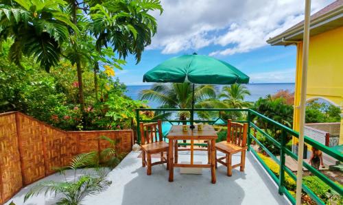 a patio with a table and a green umbrella at Camotes Harmony in Camotes Islands