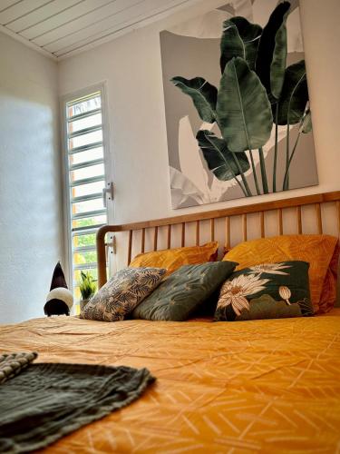 a bedroom with a bed with pillows and a painting at Chill Out, bungalow ensoleillé in Grand-Bourg