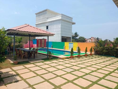 a patio with a table and a gazebo at Palm Villa and Cottage in Alibaug