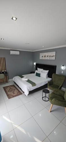 a bedroom with a large bed and two chairs at Grand Diamond Lodge in Roodepoort
