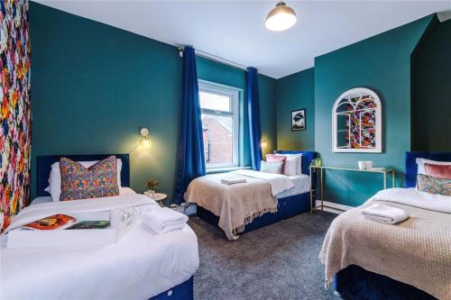 a blue room with two beds and a window at Chic & Modern Escape in Manchester