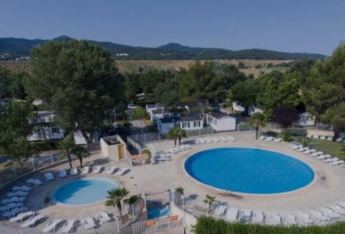 une vue aérienne d'une grande piscine avec des chaises et des arbres dans l'établissement mobil home 150 chez Valérie, à La Roque-dʼAnthéron