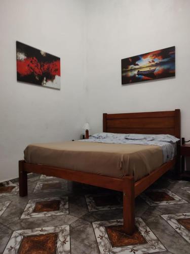 a bed in a bedroom with two pictures on the wall at Hostelmo Hotel in Buenos Aires