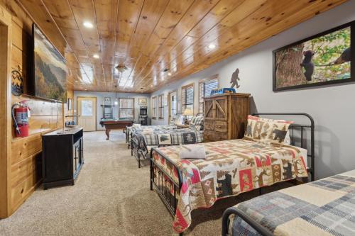 ein Schlafzimmer mit drei Betten und einem Fernseher in einem Zimmer in der Unterkunft Secluded Cubs Den Retreat in Wears Valley Sleeps 10 Hot Tub Pool Table Dog Friendly in Sevierville