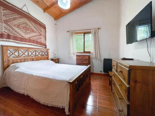 Un dormitorio con una cama y un televisor de pantalla plana. en Alojamiento Las Retamas, en El Bolsón