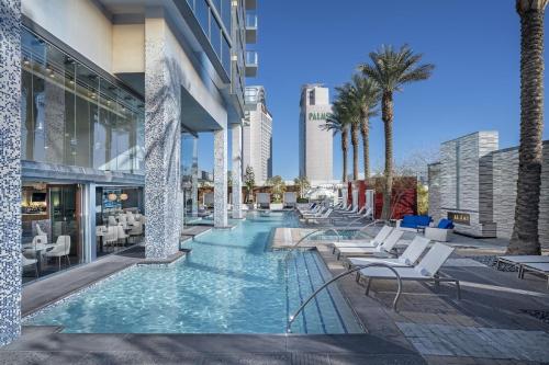 a pool with chairs and palm trees in a building at Palms Place- Strip View- High floor- Free parking in Las Vegas