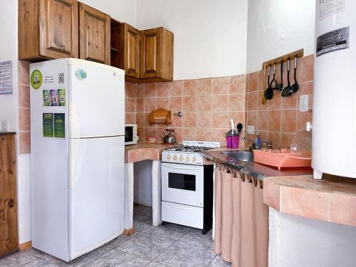 Una cocina con un refrigerador blanco y una estufa. en Alojamiento Las Retamas, en El Bolsón