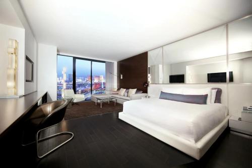 a bedroom with a large white bed and a living room at Palms Place- Strip View- High floor- Free parking in Las Vegas