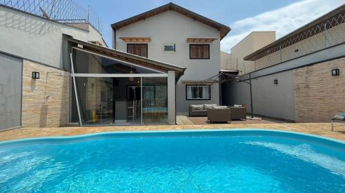 a large blue swimming pool in front of a house at Casa em condomínio em Taubaté in Taubaté