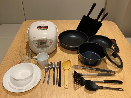 a table with plates and utensils and a food processor at My Home Inn Sennan, Onosato in Ozaki