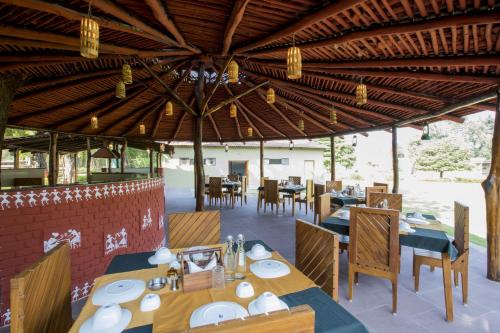 a restaurant with wooden tables and chairs and lights at PantherOn Lodge, Bandhavgarh, India in Tāla
