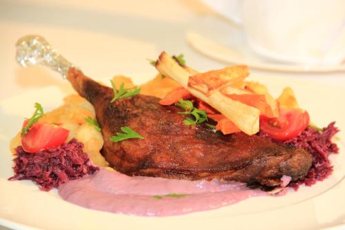 a plate of food with meat and vegetables on a table at Hotel Ózd in Ózd