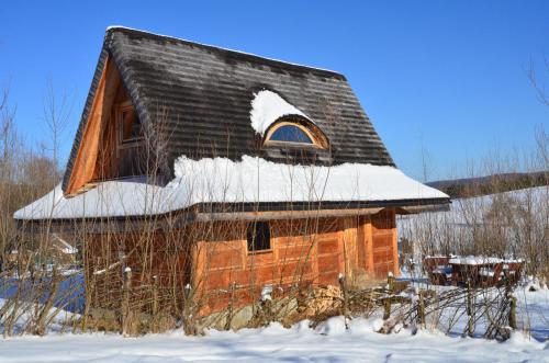 an old house with snow on the roof at Domki Osada Werdołyna in Polańczyk
