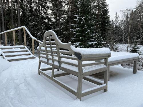 a bench covered in snow next to a staircase at Guest house and sauna with lake view in Bergshamra