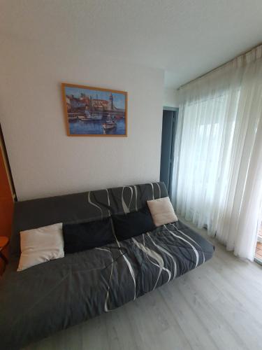 - un canapé dans une pièce avec fenêtre dans l'établissement Appartement avec piscine proche plage et commerces, à Argelès-sur-Mer
