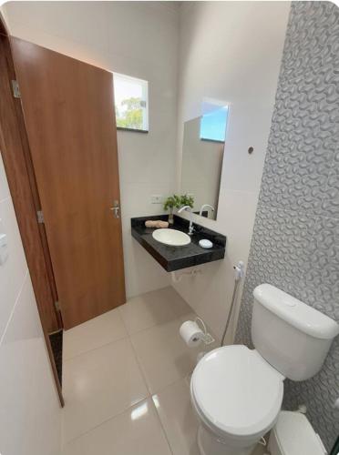 a white bathroom with a toilet and a sink at Suítes Nina e Malu in Santa Cruz Cabrália
