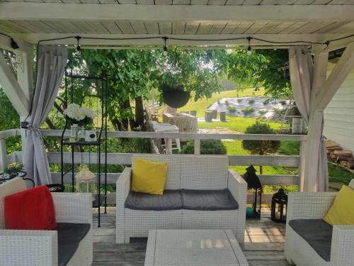 a porch with white chairs and yellow pillows at Koperkowy Raj Beskid Wyspowy Domek Małopolska Jacuzzi Playroom in Laskowa