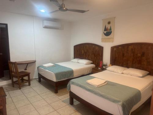 a bedroom with two beds and a table and a chair at Casa calendario azteca in Playa del Carmen