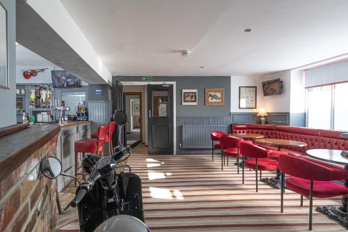 a restaurant with red chairs and tables and a bar at The Crossroads Inn in Sacriston