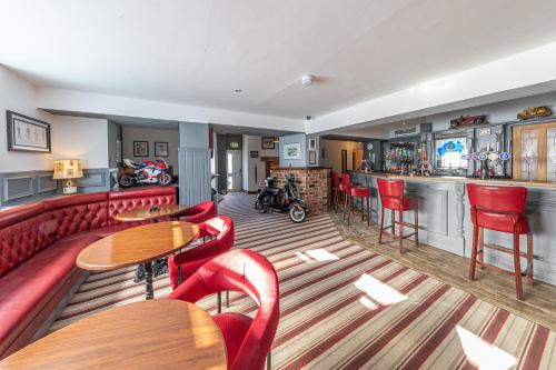 a bar with red chairs and tables in a restaurant at The Crossroads Inn in Sacriston