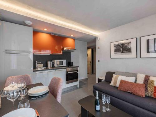 Il dispose d'une cuisine et d'un salon avec un canapé et une table. dans l'établissement Appartement cosy, design, rénové, en centre-ville avec grande chambre à Courchevel Moriond - FR-1-563-44, à Courchevel
