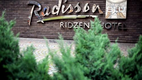 a sign on the side of a building with trees at Radisson Blu Ridzene Hotel, Riga in Rīga