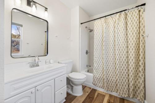 a bathroom with a sink and a toilet and a mirror at Fireside Grove- Downtown Stay with Hot Tub in Custer