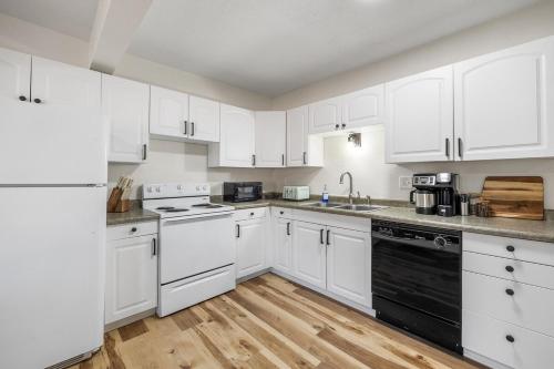 a white kitchen with white appliances and wooden floors at Fireside Grove- Downtown Stay with Hot Tub in Custer