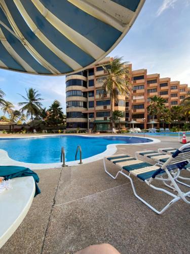 TucacasにあるApartamento Playa en Tucacasのラウンジチェア付きのスイミングプール、