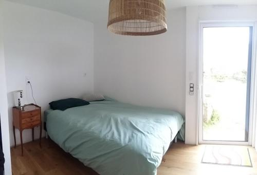 une chambre blanche avec un lit et une fenêtre dans l'établissement Au bord de la Ria, à Locoal-Mendon