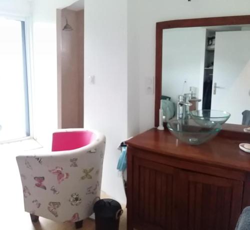 La salle de bains est pourvue d'un comptoir, d'une chaise et d'un miroir. dans l'établissement Au bord de la Ria, à Locoal-Mendon